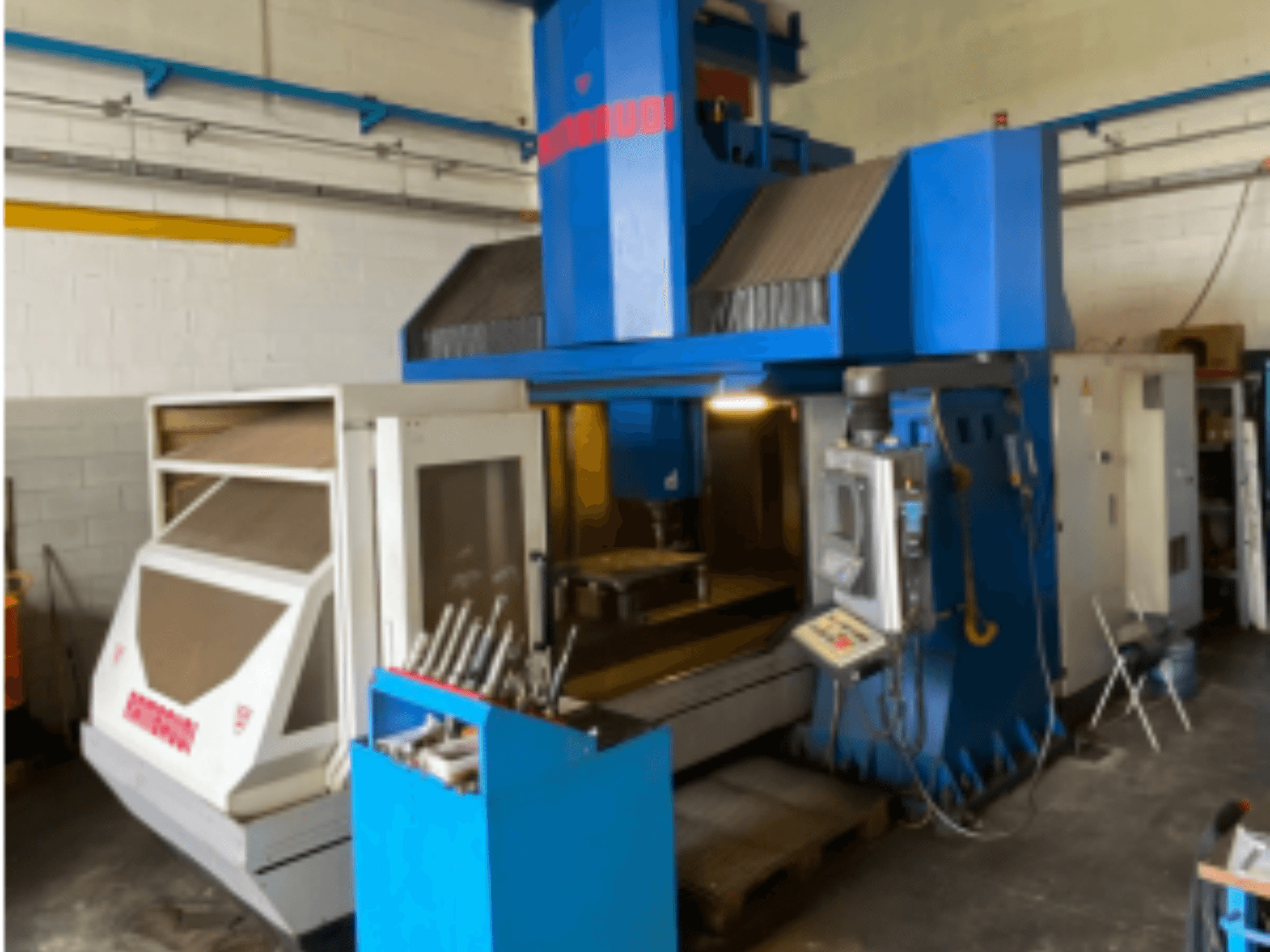 Vertical machining center Rambaudi RF103, front view showing controls, tool storage, and machining area. Blue and white exterior.