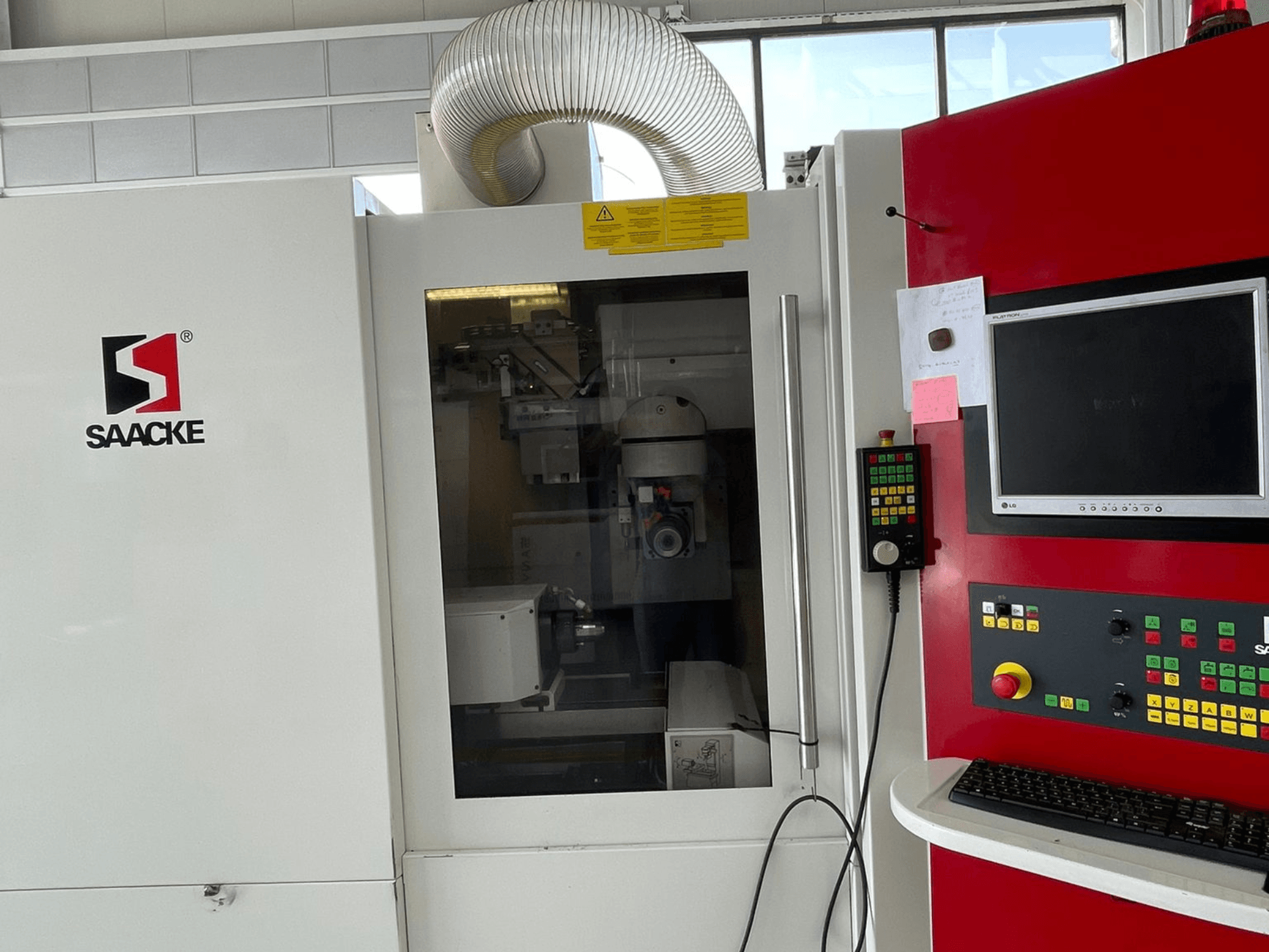 SAACKE machine in white and red, front view, features a control panel, monitor, and visible internal parts through glass.