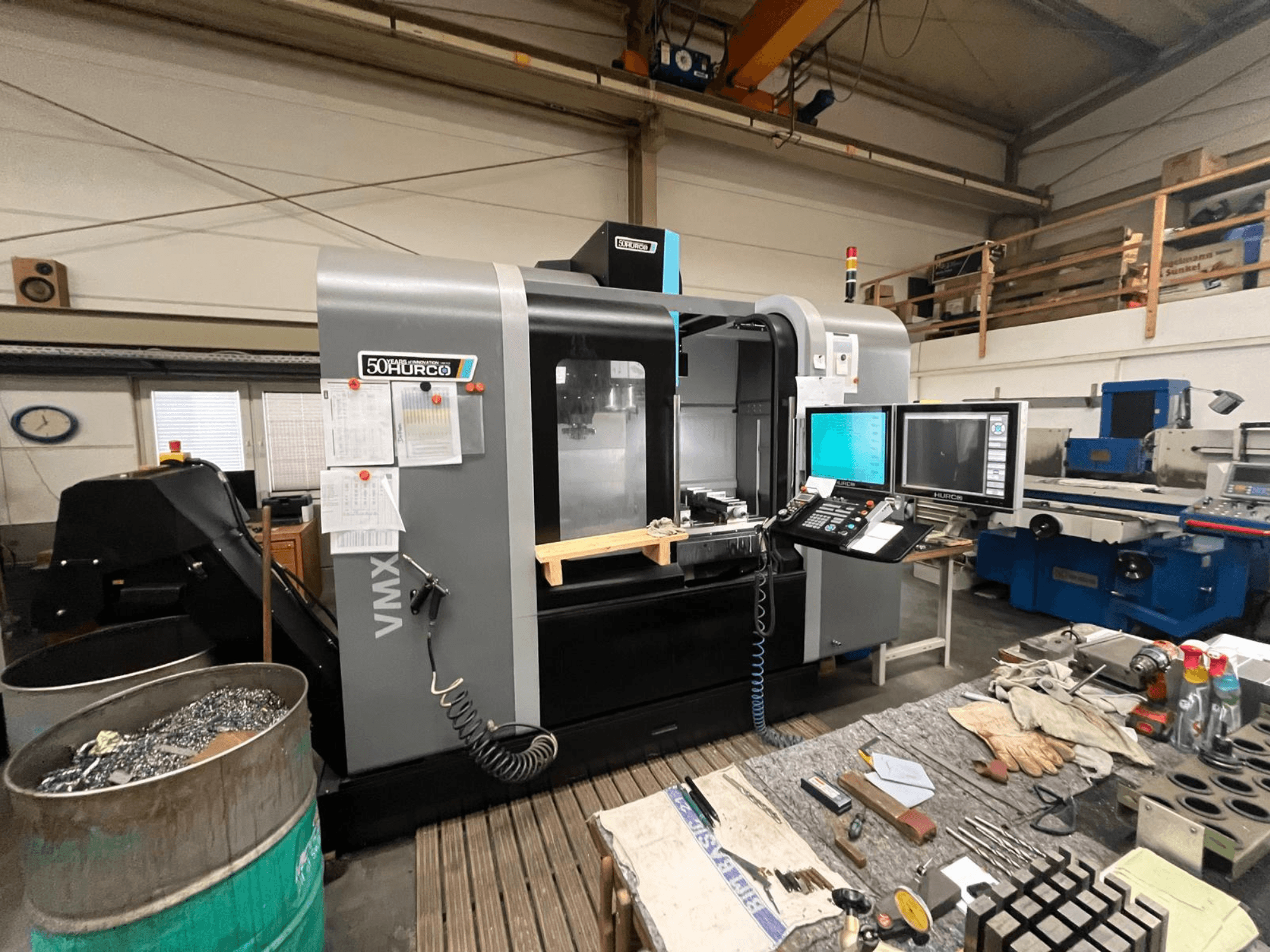 Hurco VMX 50 CNC milling machine in a workshop, front view with control panel and cluttered workbench.