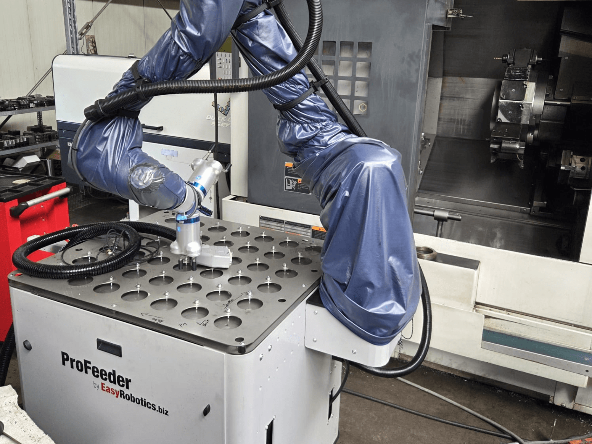 Collaborative robot EASYROBOTICS ProFeeder from a front view, with a robotic arm positioned over a perforated metal table.