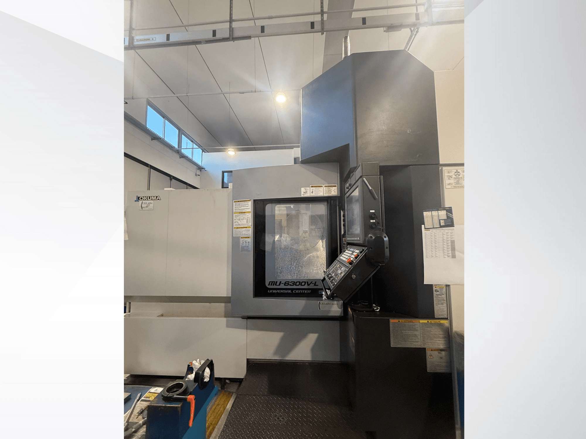 Okuma MU-6300V-L CNC machine viewed from the front, showcasing control panel and safety labels.
