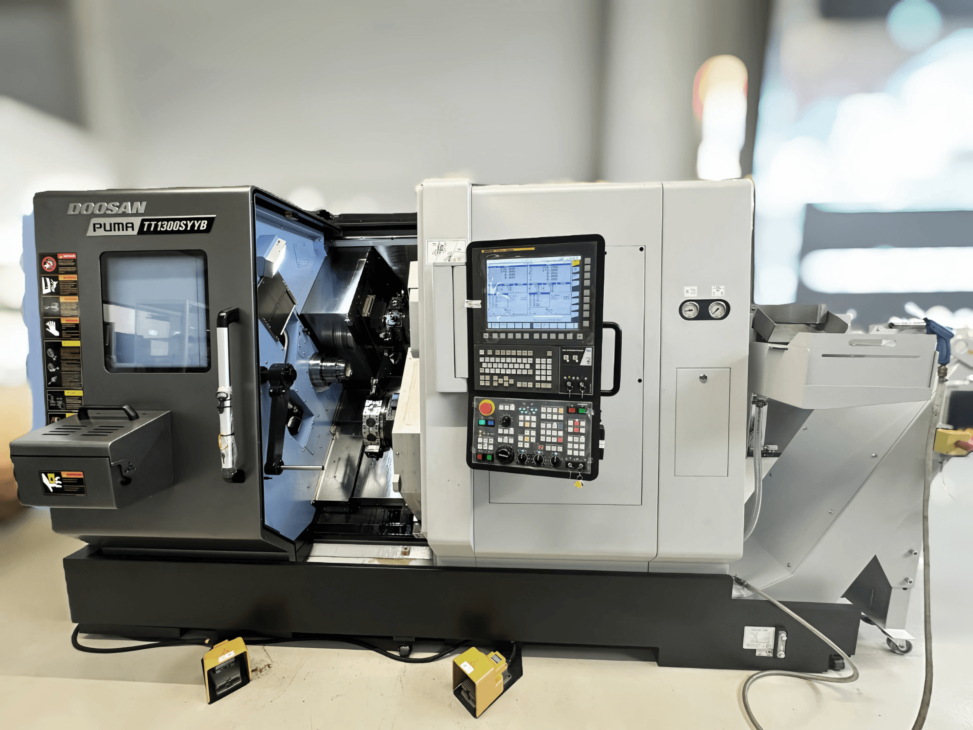 Doosan Puma TT1300SYYB turn-mill centre in side view, showcasing control panel and machine interior with tools visible.