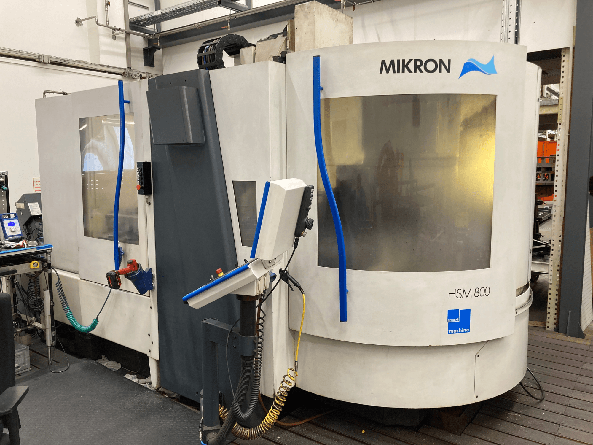 Mikron HSM 800, side view of a CNC machining center with control panel and tool holder, visible hoses and cables.