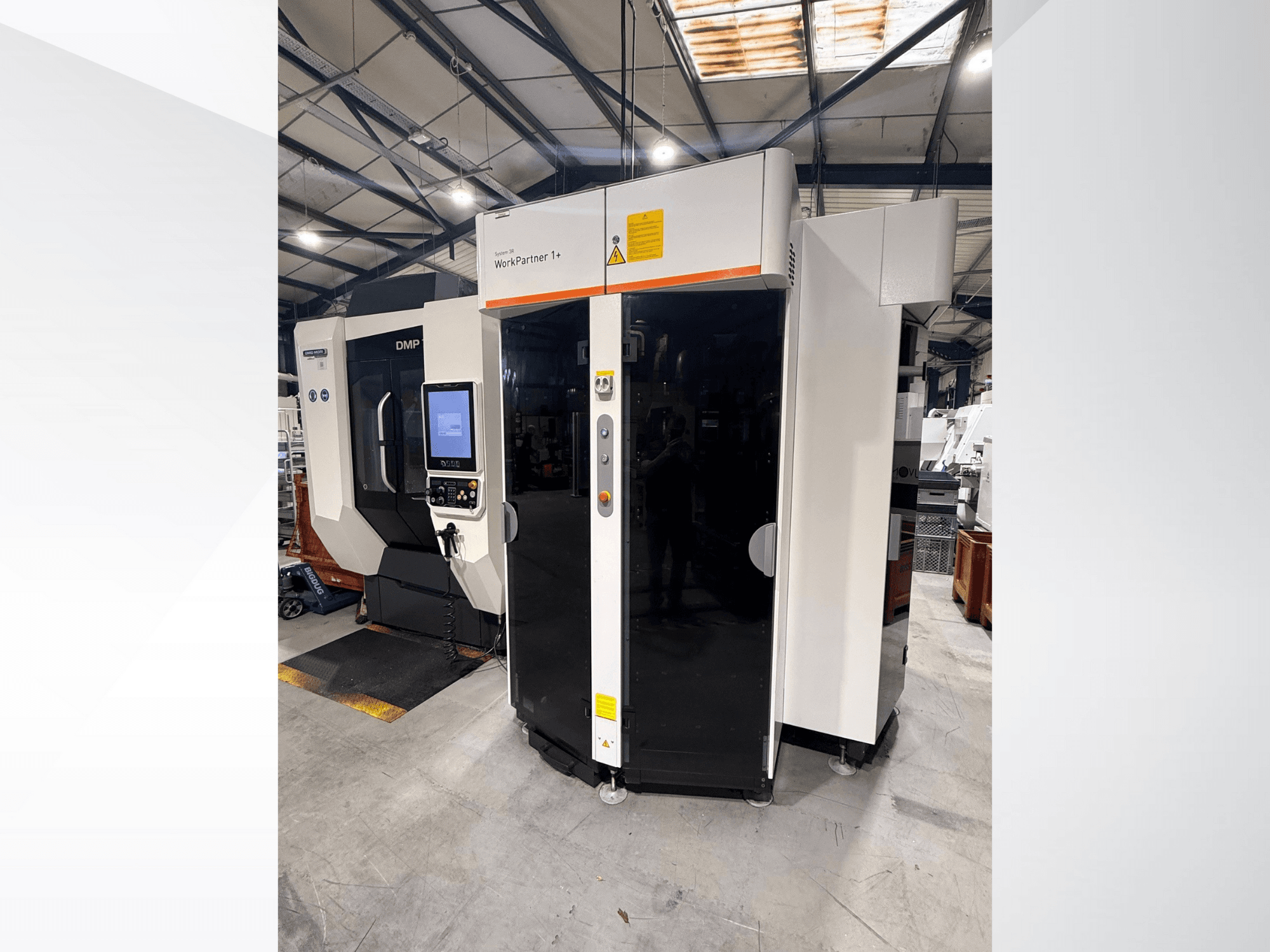 DMP WorkPartner 1+, front view; features a touchscreen panel and safety indicators in a manufacturing setting.