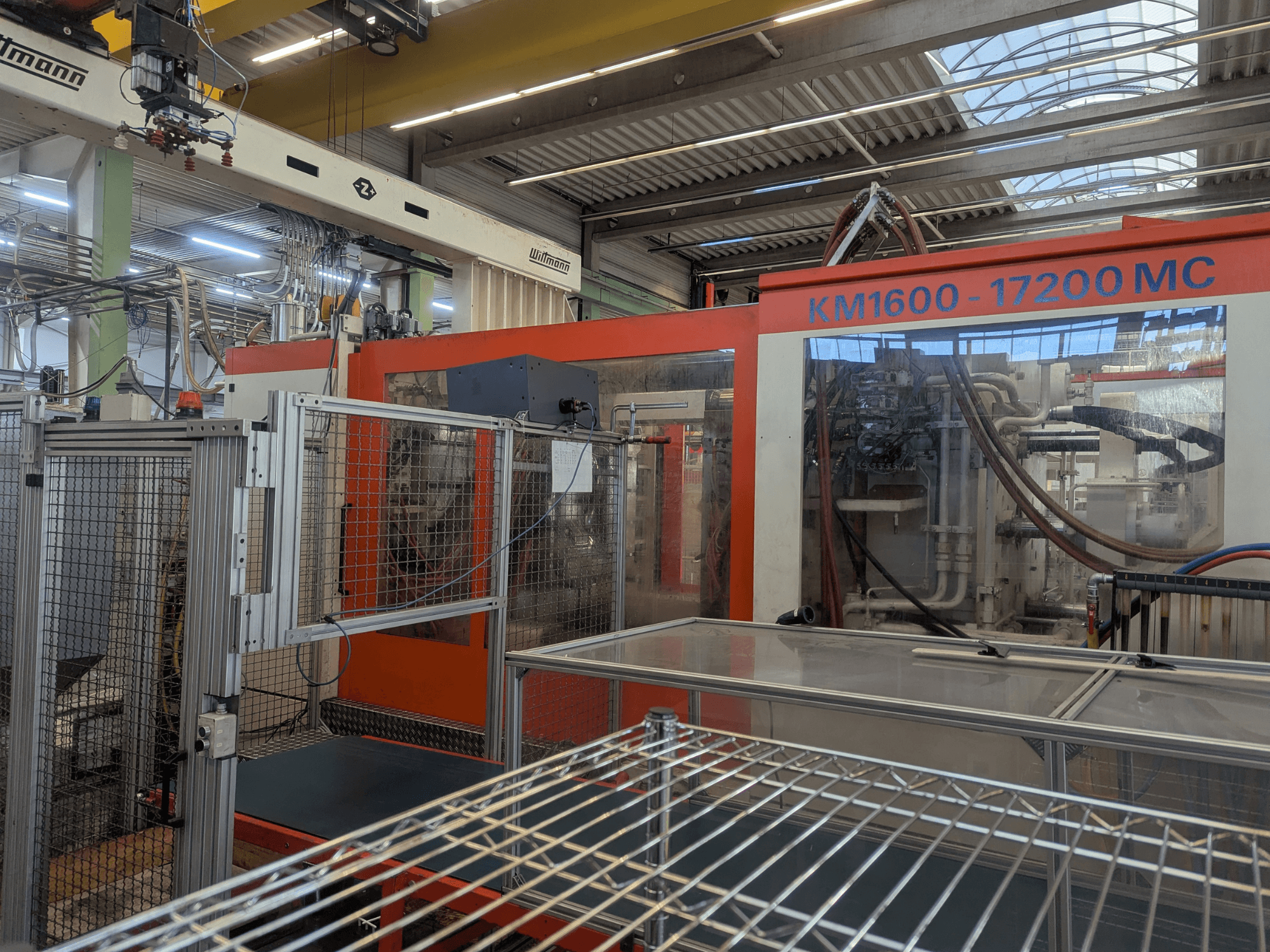 Hydraulic injection moulding machine Krauss Maffei KM 1600-17200MC, front view with visible control panel and hydraulic lines.