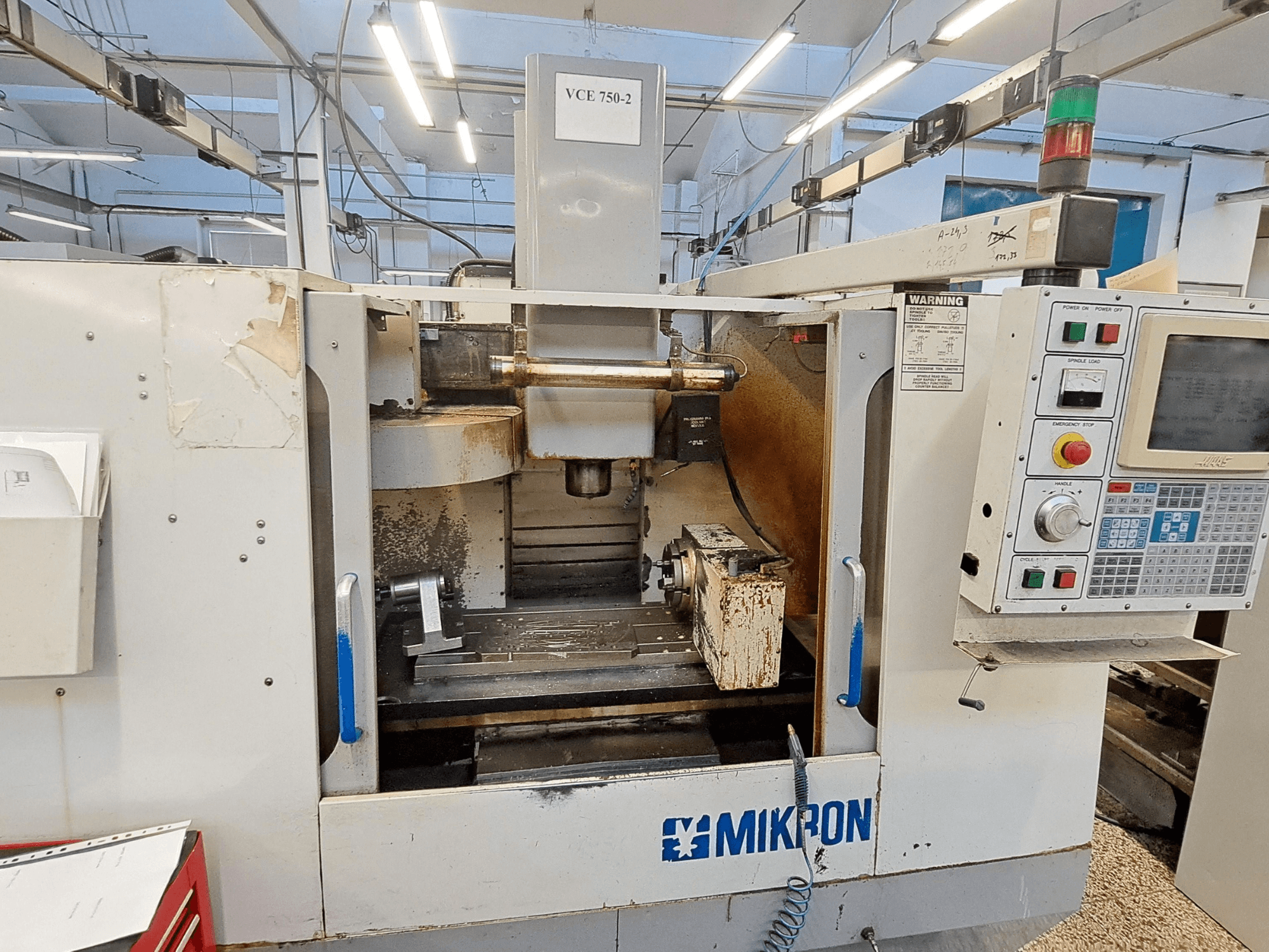Mikron VCE 750-2 CNC milling machine, front view, featuring control panel and spindle in machining area, shows wear and grime.